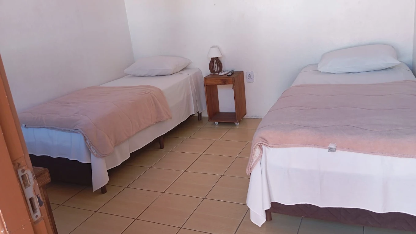 Quarto com duas camas de solteiro e mesa de cabeceira